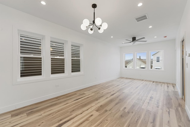 empty room with ceiling fan with notable chandelier and light wood-type flooring