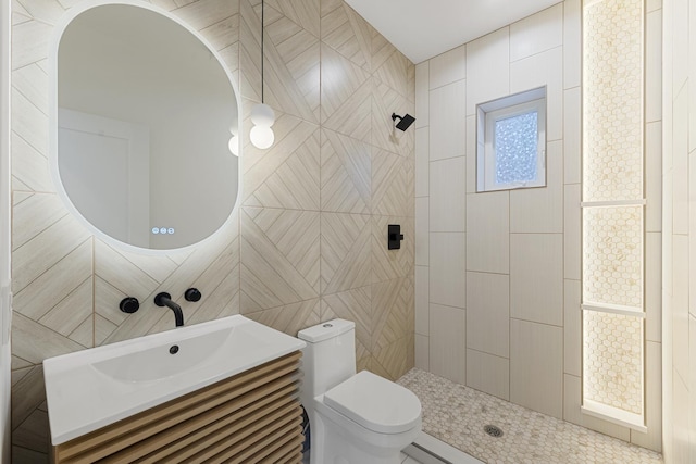 bathroom with vanity, toilet, and a tile shower