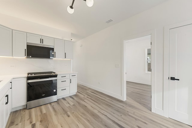 kitchen featuring white cabinetry, stainless steel range with gas stovetop, backsplash, and light wood-type flooring