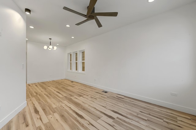 empty room featuring ceiling fan with notable chandelier and light hardwood / wood-style flooring