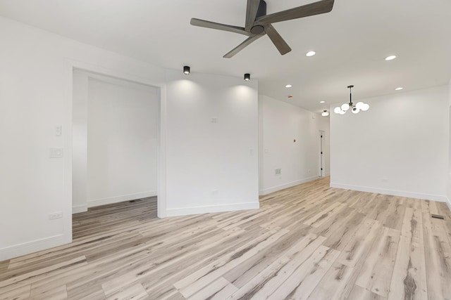 empty room featuring ceiling fan with notable chandelier and light hardwood / wood-style flooring