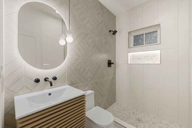 bathroom featuring vanity, a tile shower, and toilet