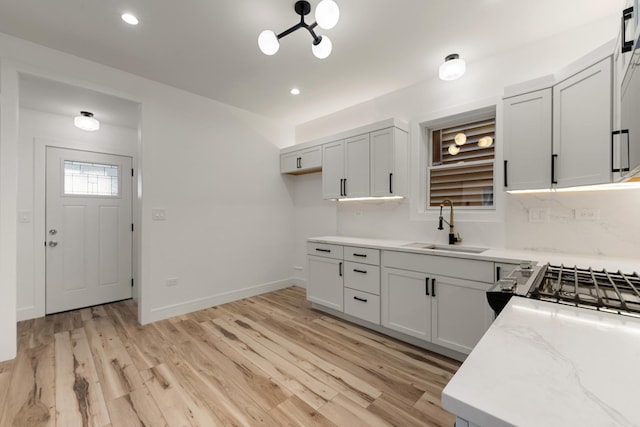 kitchen featuring sink, light hardwood / wood-style floors, range, and light stone countertops