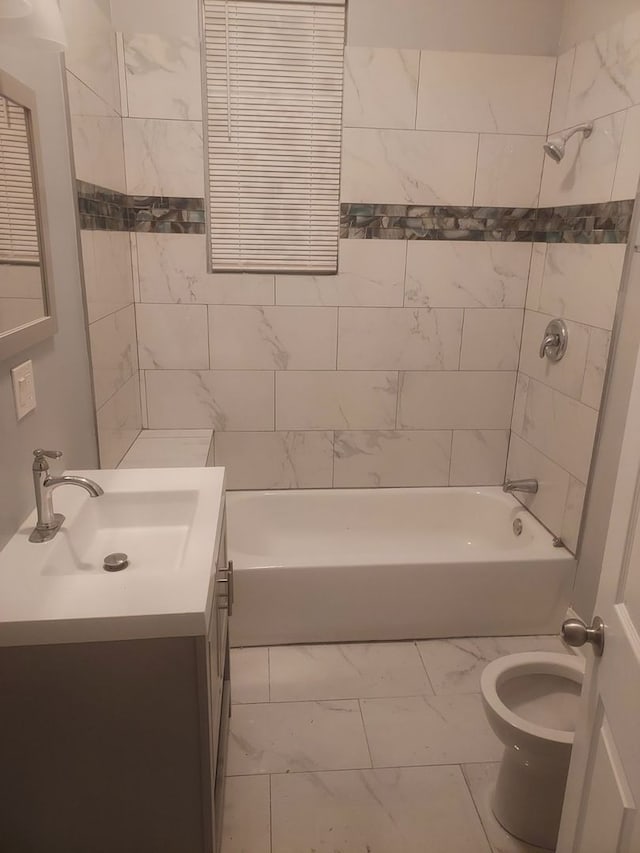 full bathroom featuring vanity, tiled shower / bath, and toilet