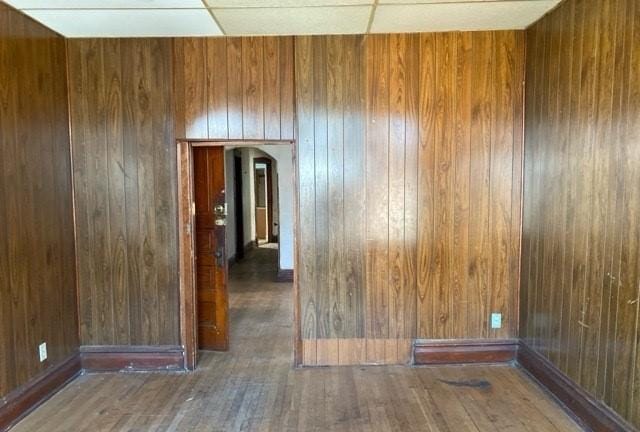 unfurnished room featuring dark hardwood / wood-style flooring and wooden walls