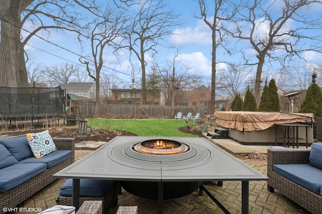 view of patio / terrace featuring a hot tub, an outdoor living space with a fire pit, and a trampoline