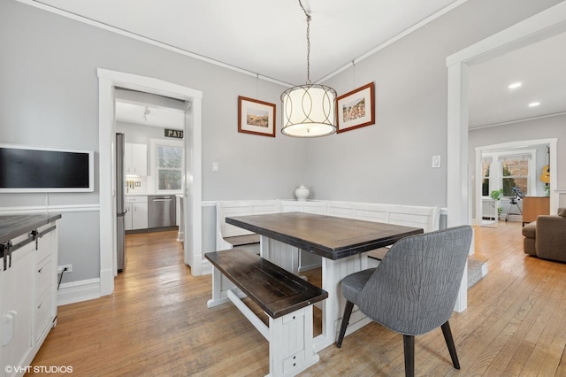 dining space featuring crown molding and light hardwood / wood-style flooring