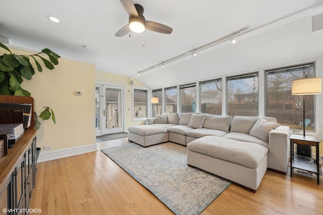 living room with vaulted ceiling, rail lighting, ceiling fan, and light hardwood / wood-style floors