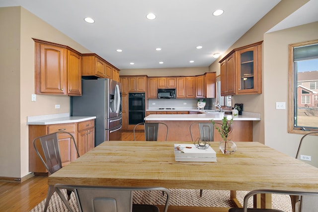 kitchen featuring a wealth of natural light, black appliances, sink, a kitchen breakfast bar, and kitchen peninsula