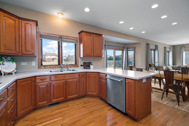 kitchen featuring sink, stainless steel dishwasher, kitchen peninsula, and light wood-type flooring