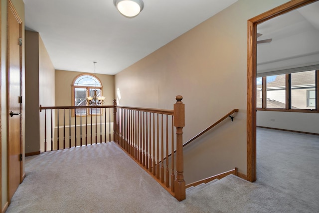 hall with light carpet and a notable chandelier