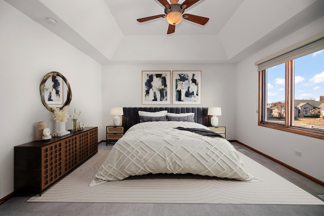 bedroom with ceiling fan, carpet flooring, and a raised ceiling