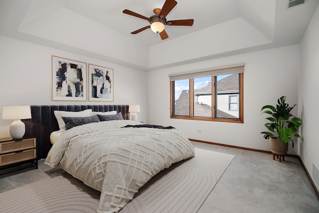 bedroom featuring a tray ceiling, light colored carpet, and ceiling fan