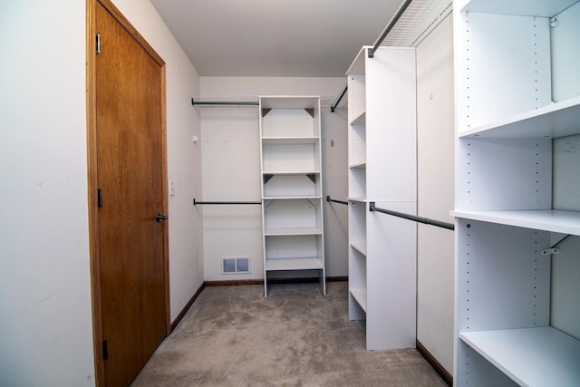 walk in closet featuring light colored carpet