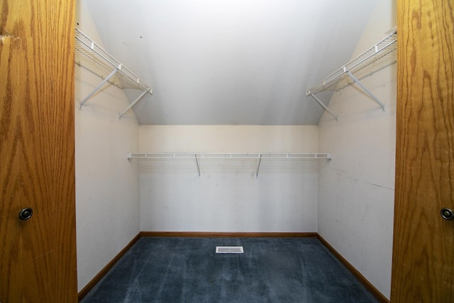 walk in closet featuring lofted ceiling and dark colored carpet