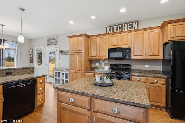 kitchen with stone countertops, black appliances, a center island, and light wood-type flooring