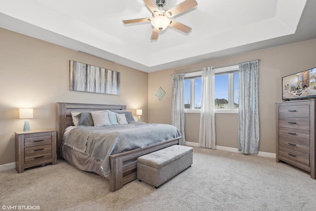 bedroom featuring ceiling fan, light colored carpet, and a raised ceiling