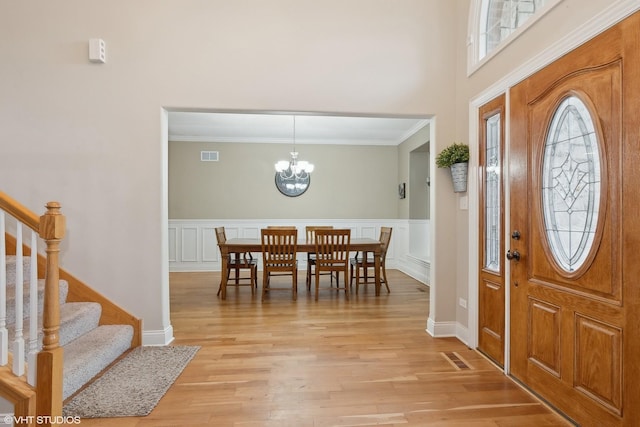 foyer entrance with ornamental molding, a chandelier, and light hardwood / wood-style flooring