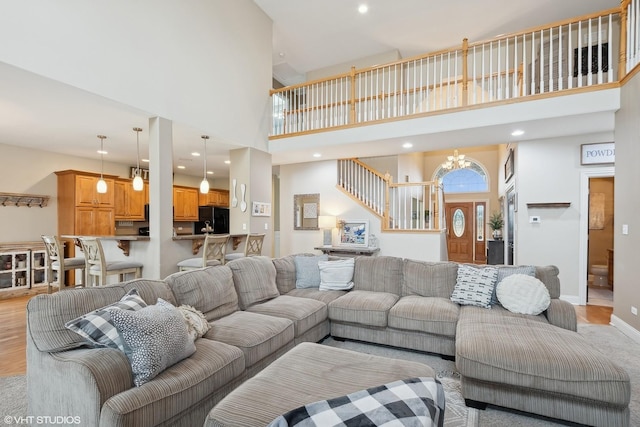 living room featuring an inviting chandelier, light hardwood / wood-style floors, and a high ceiling