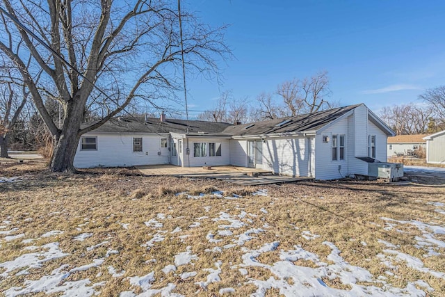 snow covered back of property featuring a patio