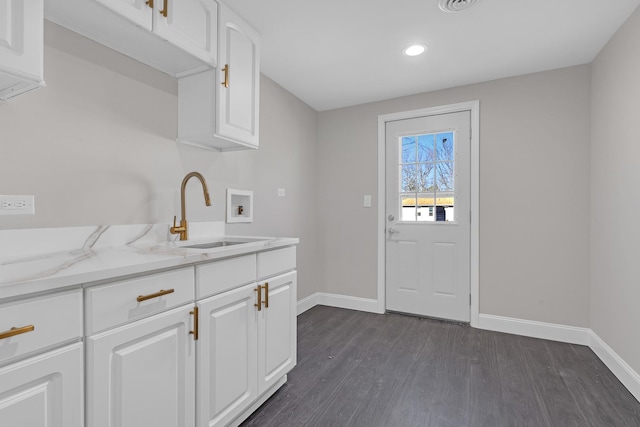 kitchen with dark hardwood / wood-style flooring, light stone countertops, sink, and white cabinets