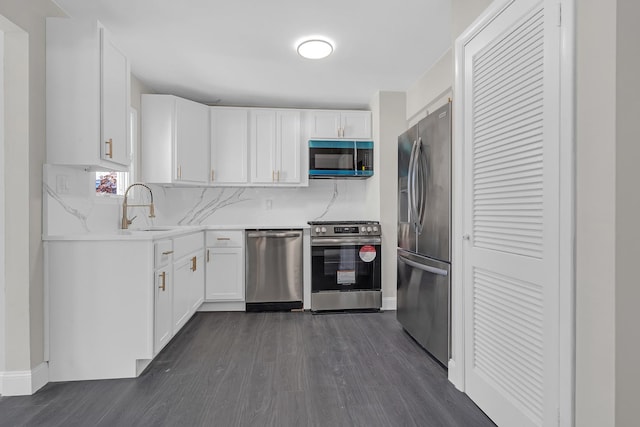 kitchen featuring sink, appliances with stainless steel finishes, white cabinetry, dark hardwood / wood-style floors, and decorative backsplash