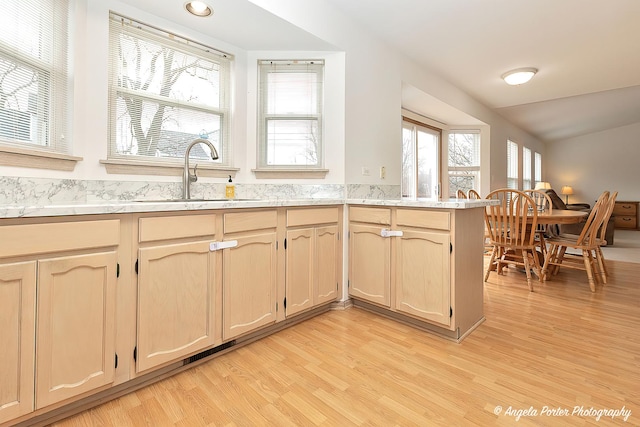 kitchen with light hardwood / wood-style floors, kitchen peninsula, sink, and light brown cabinets