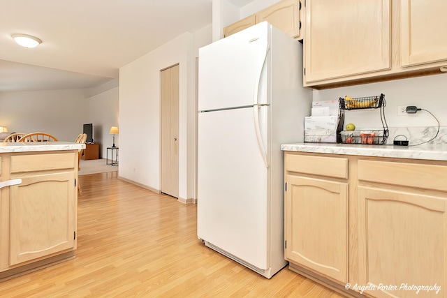 kitchen with light brown cabinets, light hardwood / wood-style floors, and white fridge