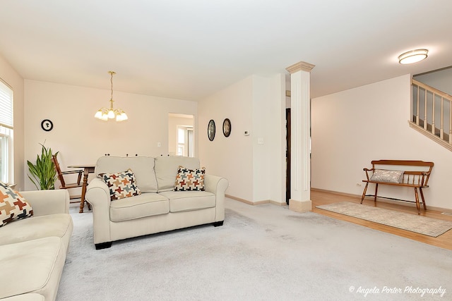 living room with an inviting chandelier, decorative columns, and light carpet