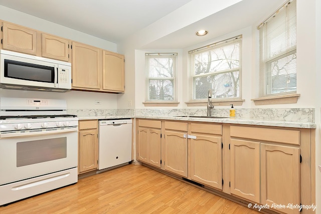 kitchen featuring sink, light brown cabinetry, white appliances, and light wood-type flooring