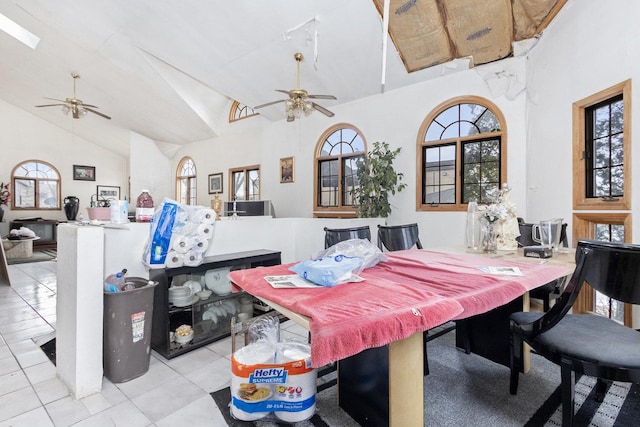 dining area with light tile patterned flooring, ceiling fan, and high vaulted ceiling