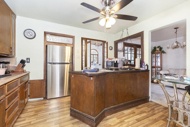 kitchen featuring stainless steel refrigerator, kitchen peninsula, light hardwood / wood-style flooring, and pendant lighting