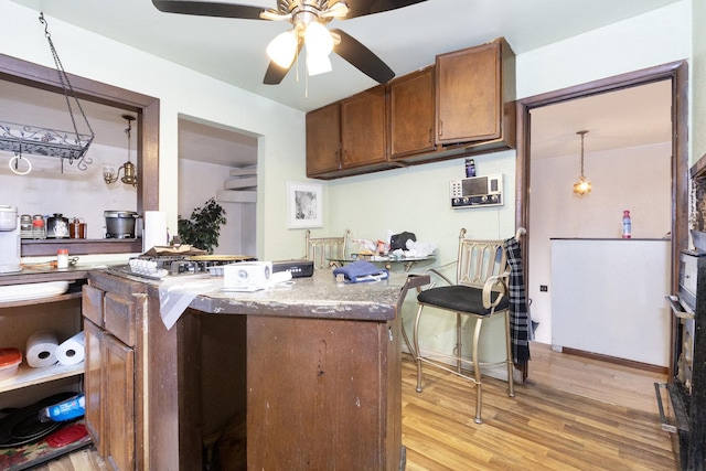 kitchen featuring hanging light fixtures, light hardwood / wood-style flooring, kitchen peninsula, ceiling fan, and light stone countertops