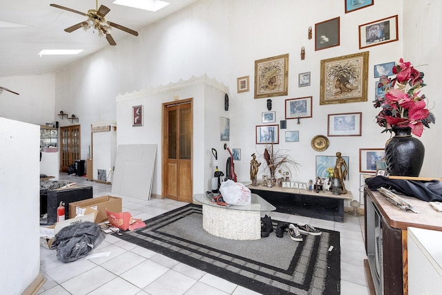 misc room featuring light tile patterned floors, a skylight, high vaulted ceiling, and ceiling fan