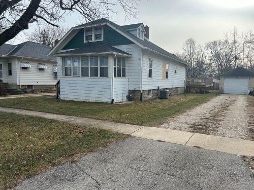 view of side of home with a garage, an outdoor structure, a lawn, and central air condition unit