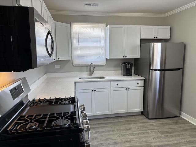 kitchen with stainless steel appliances, white cabinetry, sink, and crown molding