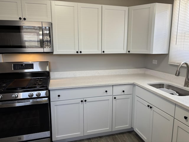 kitchen featuring sink, appliances with stainless steel finishes, dark hardwood / wood-style flooring, light stone countertops, and white cabinets