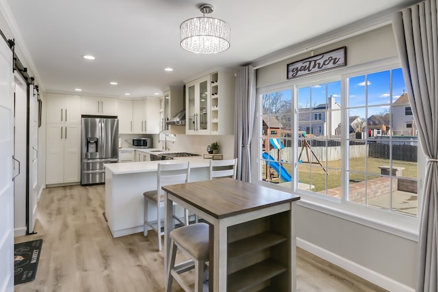 kitchen featuring white cabinetry, hanging light fixtures, appliances with stainless steel finishes, kitchen peninsula, and a barn door