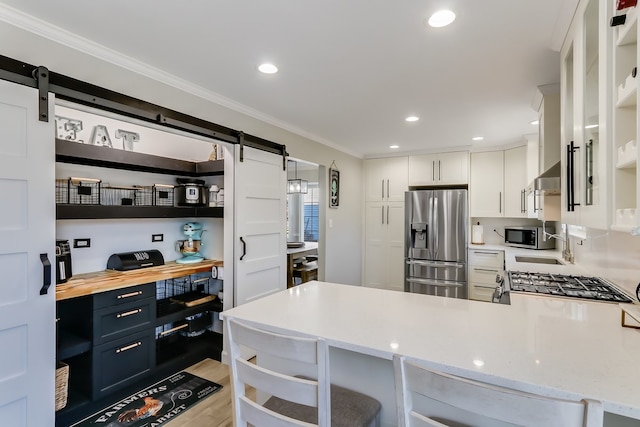 kitchen featuring a breakfast bar, blue cabinets, white cabinetry, stainless steel appliances, and a barn door