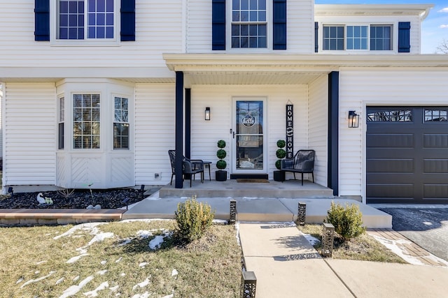 view of exterior entry featuring a garage and covered porch