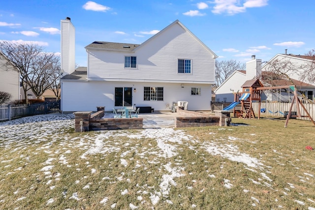 snow covered rear of property featuring a playground, a lawn, and a patio area