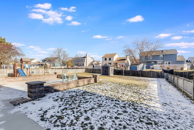 yard covered in snow featuring a playground and a storage unit