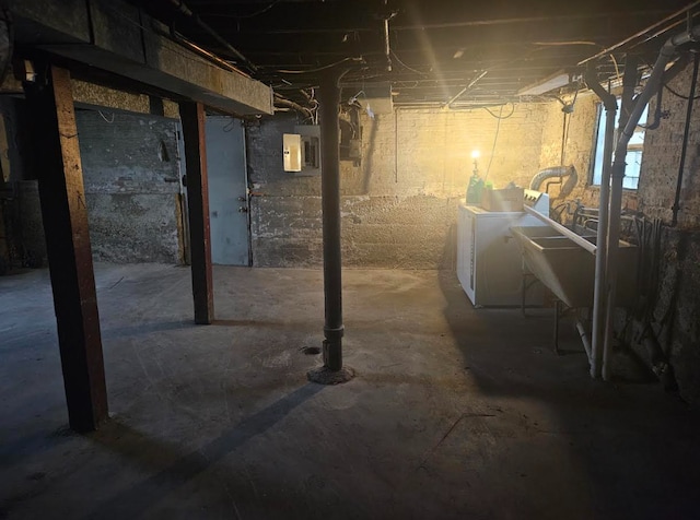 basement featuring washing machine and clothes dryer and electric panel