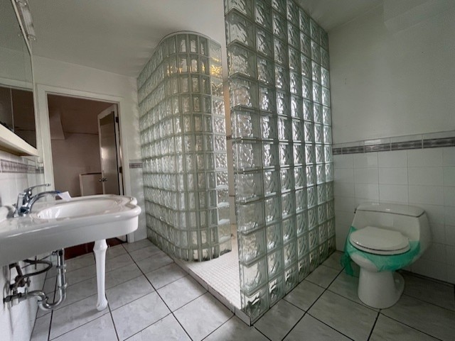 bathroom featuring tile walls, tile patterned floors, toilet, and walk in shower