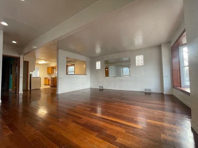 unfurnished living room with beam ceiling and dark hardwood / wood-style floors