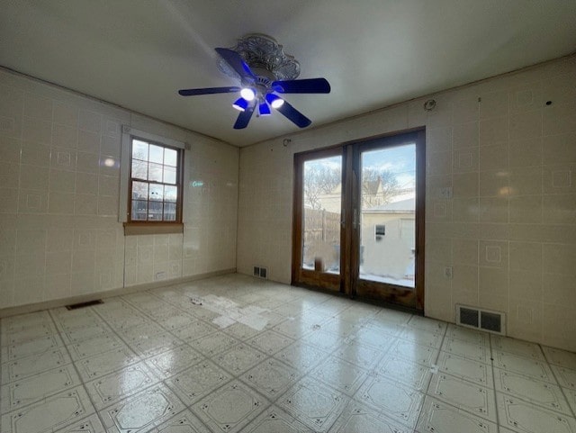 empty room with ceiling fan and tile walls