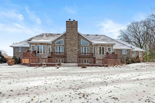 snow covered back of property with a deck