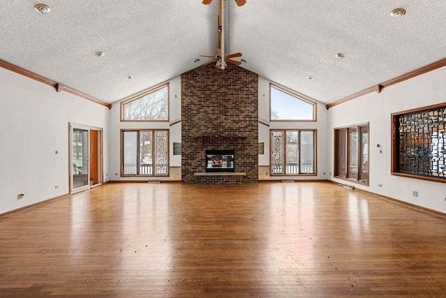 unfurnished living room featuring a brick fireplace, a textured ceiling, high vaulted ceiling, and light hardwood / wood-style flooring