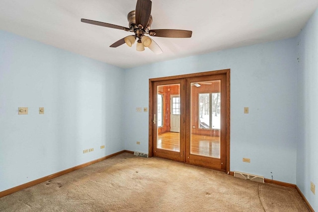 carpeted spare room featuring french doors and ceiling fan