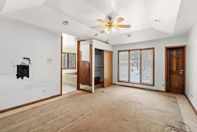 unfurnished bedroom featuring light colored carpet, a raised ceiling, and ceiling fan